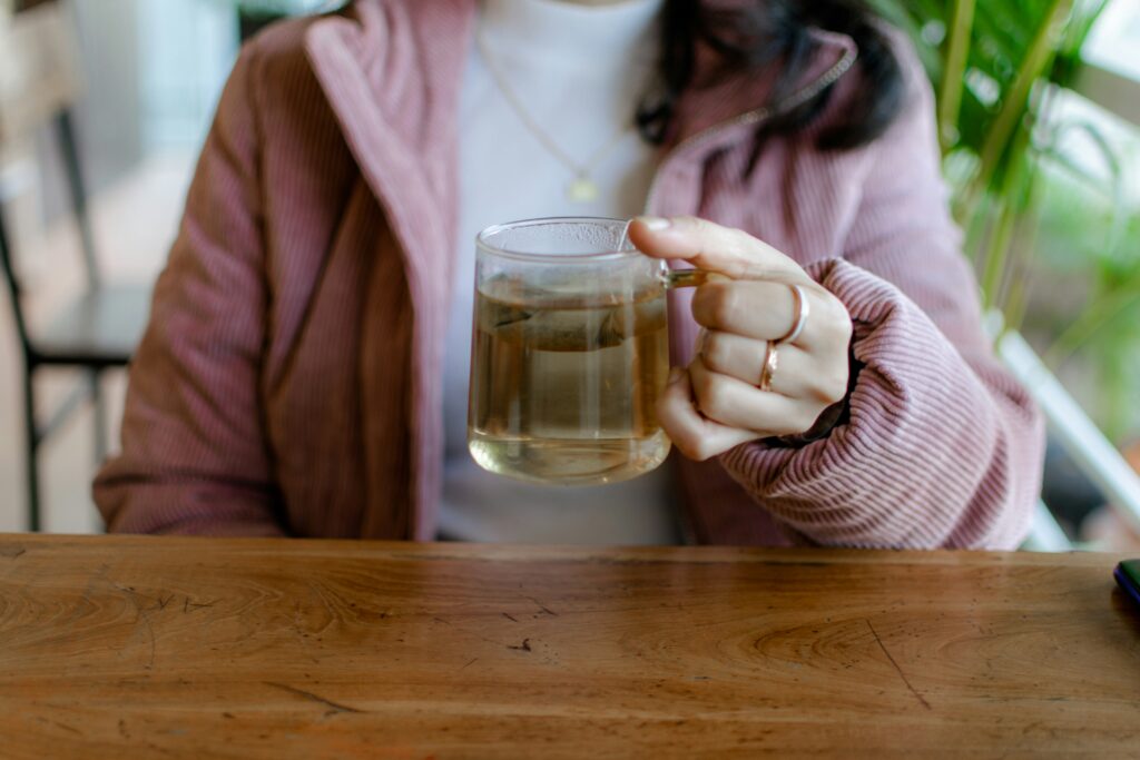 A woman holding a clear glass of tea