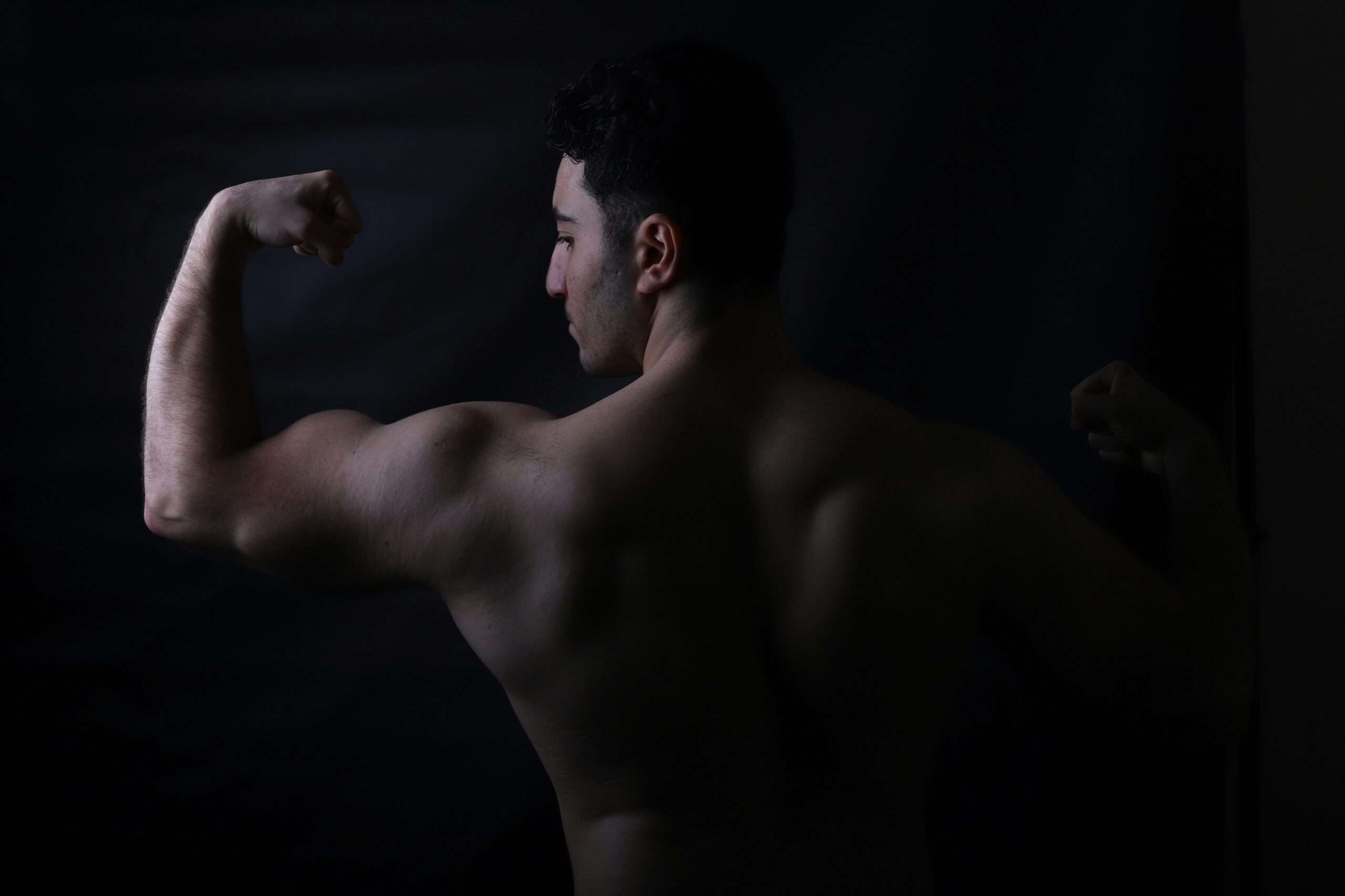 A dark silhouette of a man's back muscles